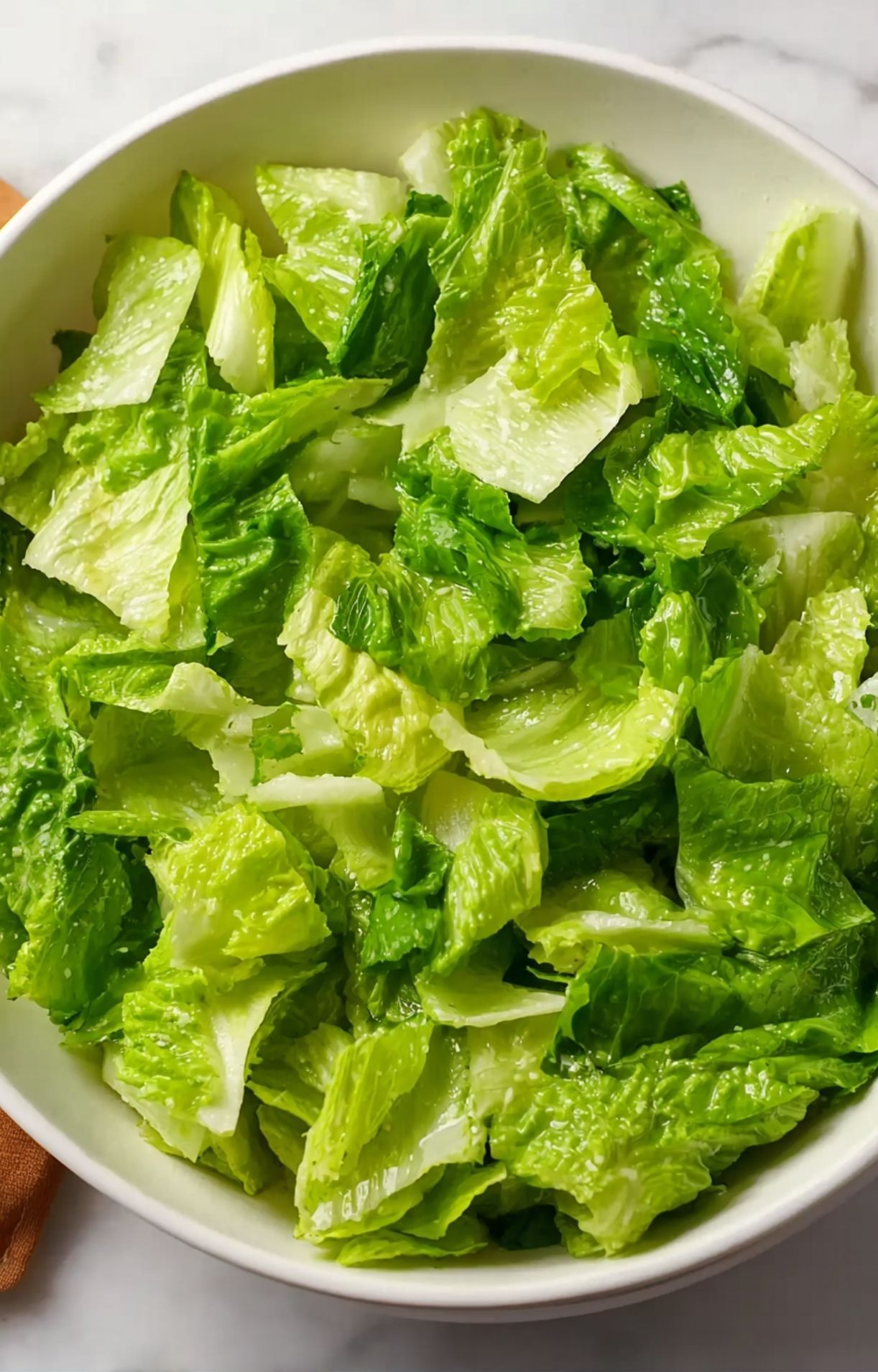 A white bowl filled with freshly chopped, bright green romaine lettuce, serving as the crisp base for an Easy Steak Taco Salad Recipe.