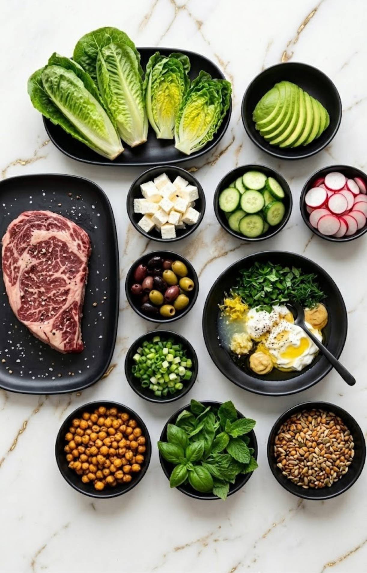 A flat-lay display of all fresh ingredients for an Easy Steak Salad Recipe, including raw steak, romaine, radishes, olives, chickpeas, and homemade dressing.