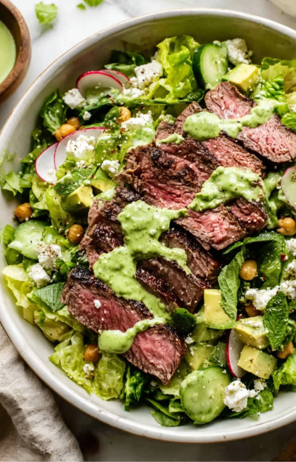 A detailed close-up of an Easy Steak Salad Recipe highlighting the textures of creamy avocado, crisp cucumbers, and tender steak topped with herb dressing.
