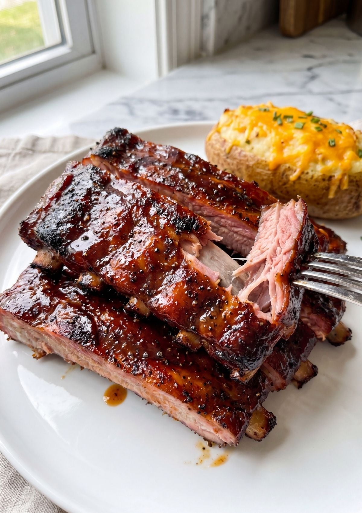 tender spare ribs pulled apart with fork showing fall off the bone texture and bbq glaze