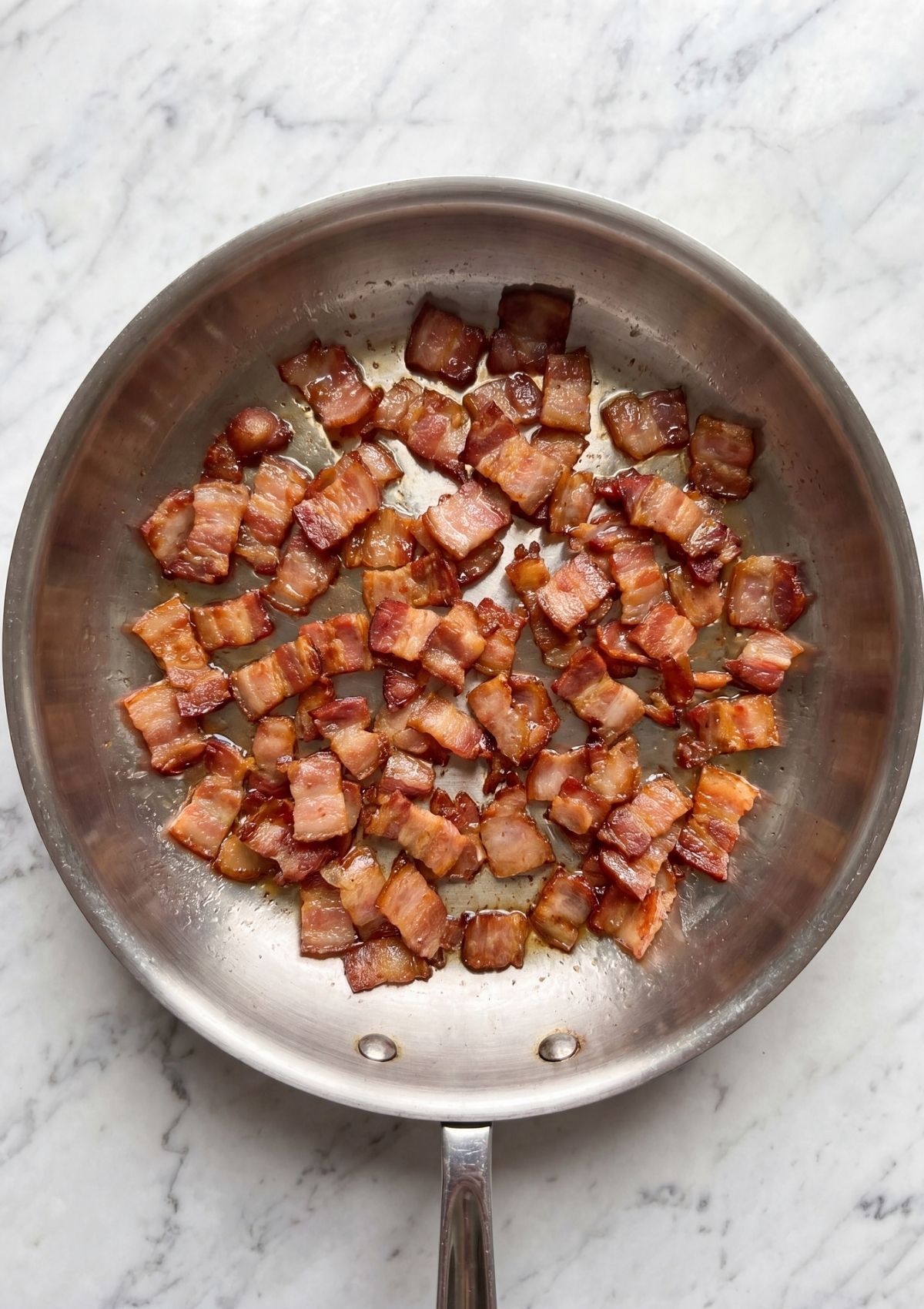 crispy chopped bacon cooking in skillet for cowboy spaghetti with bacon recipe base flavor