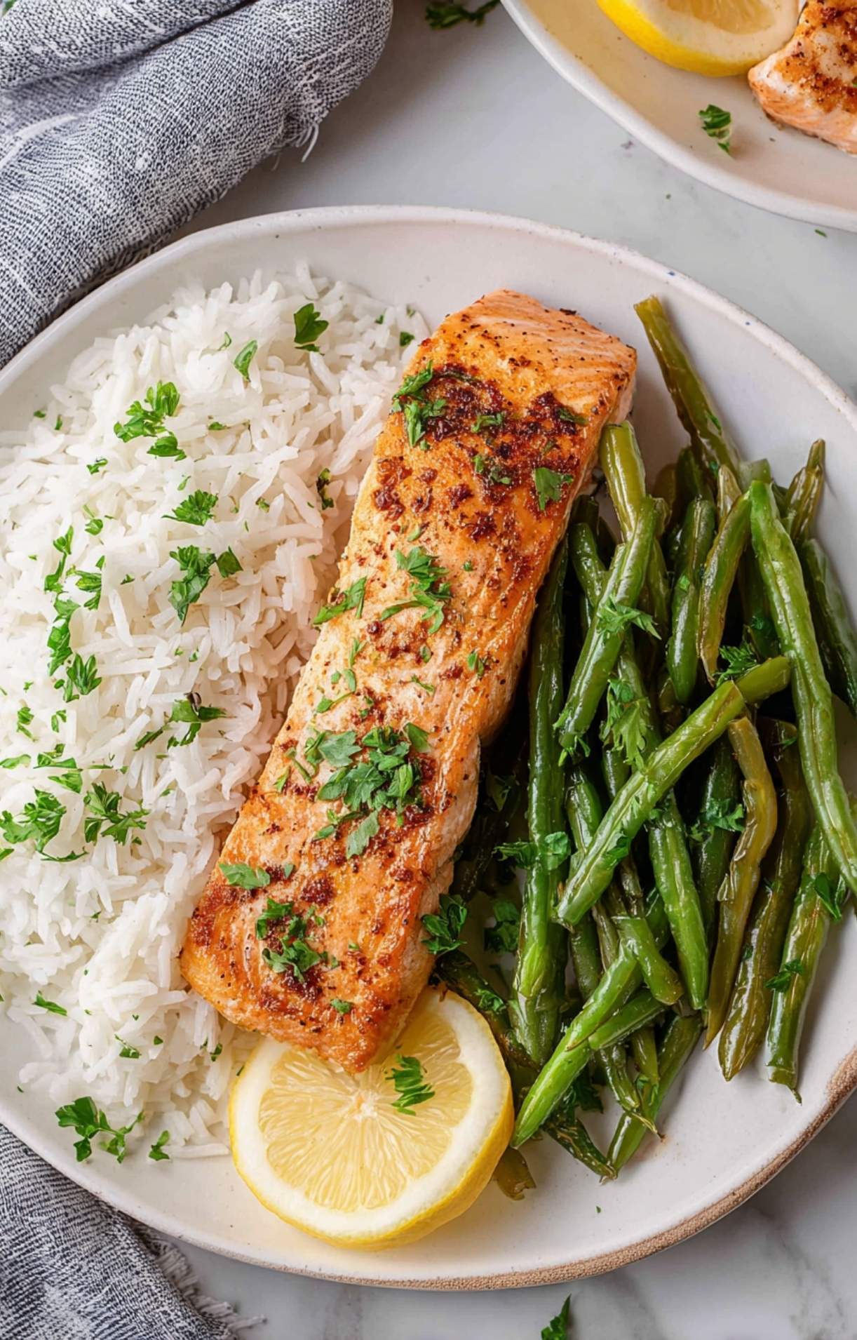 Four golden-brown fillets prepared using an easy air fryer salmon recipe, garnished with fresh parsley and lemon slices.