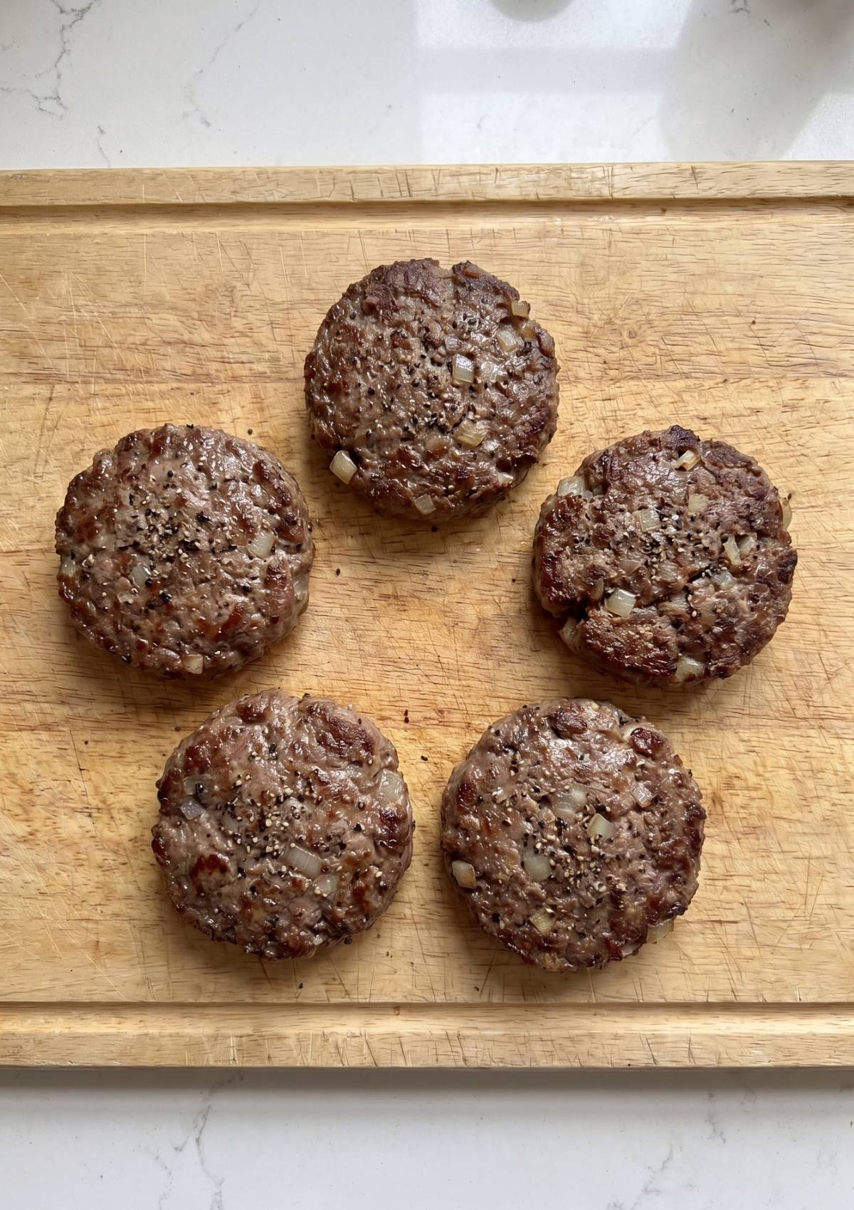 wagyu beef slider patties cooked with onions on skillet juicy homemade burger patties