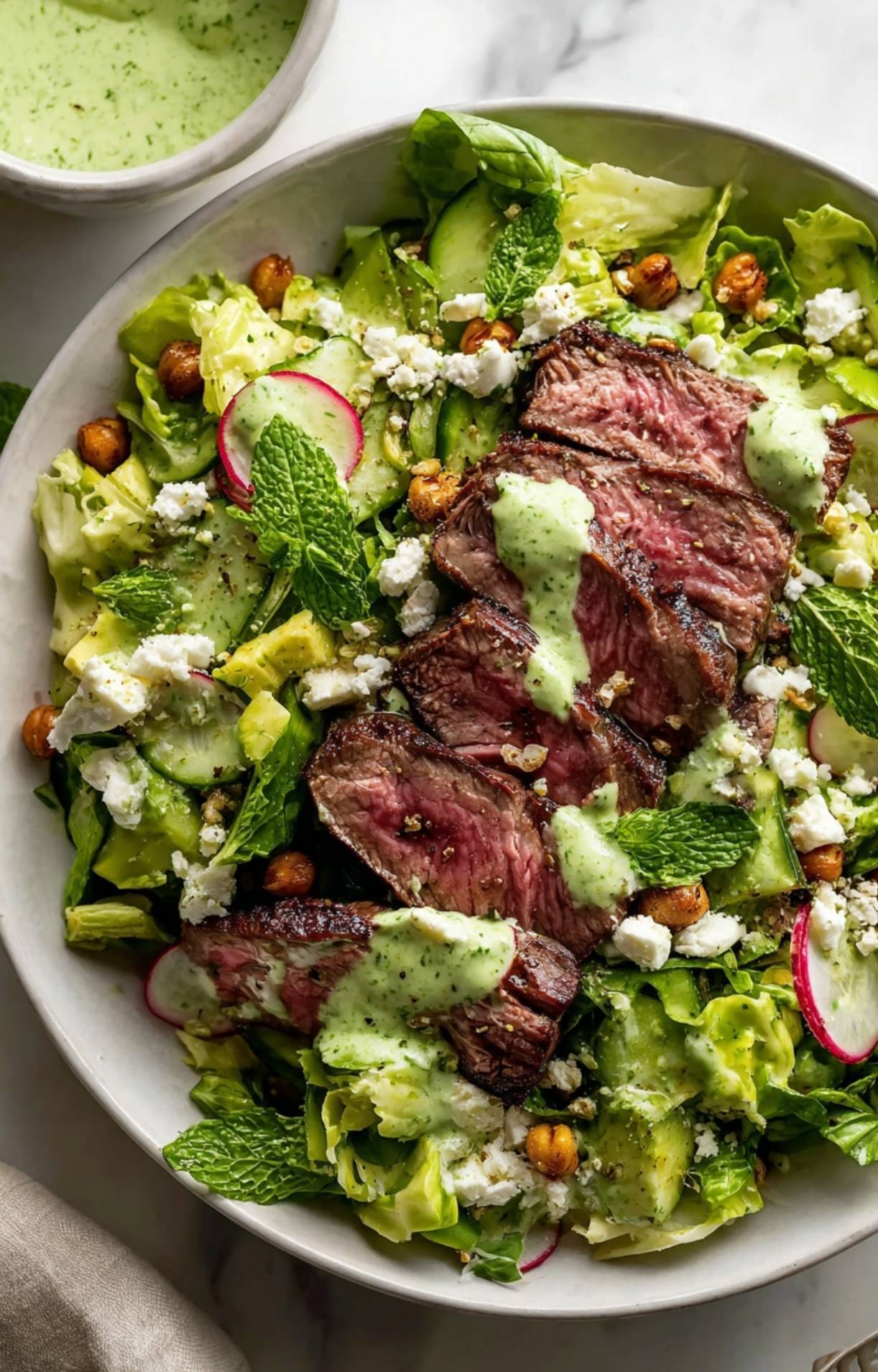 A beautifully plated Easy Steak Salad Recipe garnished with fresh mint leaves, roasted chickpeas, and crumbled cheese.