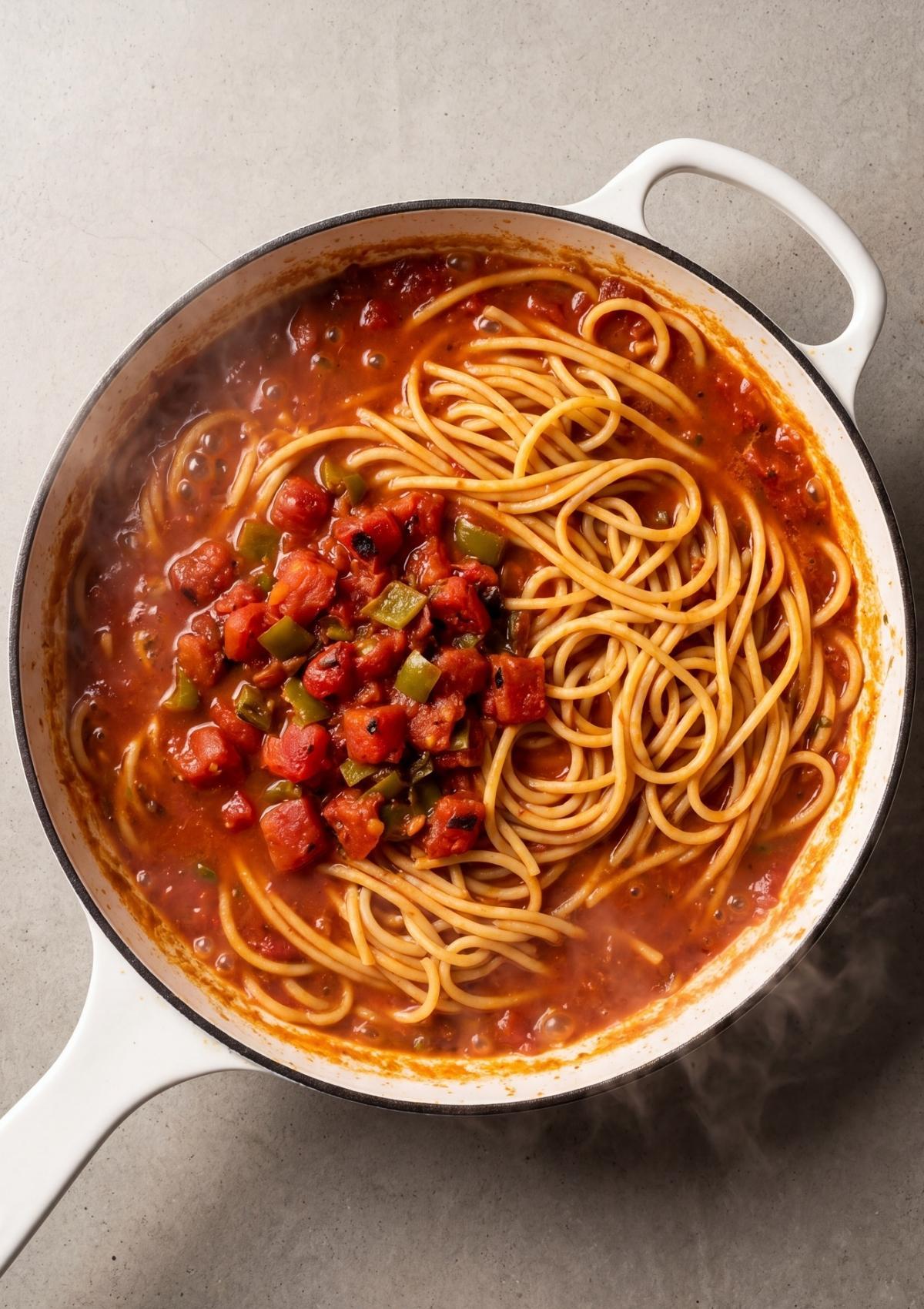 spaghetti cooking in tomato beef sauce for cowboy spaghetti recipe