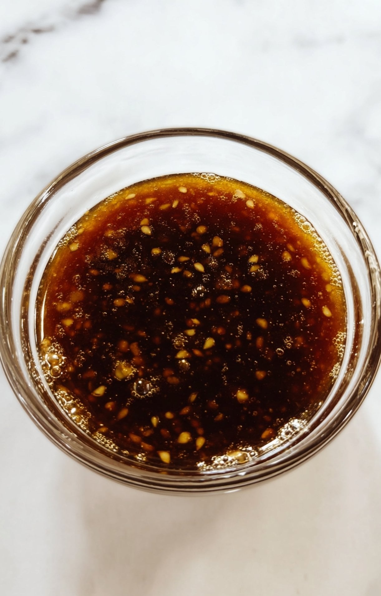 A top-down view of the honey garlic sauce with sesame seeds and minced garlic, ready to be brushed onto the salmon.