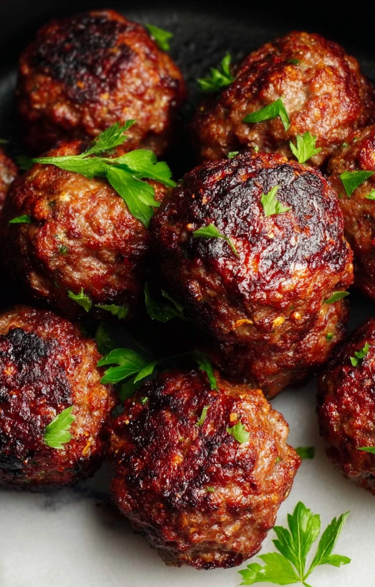 A detailed macro shot of the seared texture and fresh herb garnish on air fryer beef meatballs.