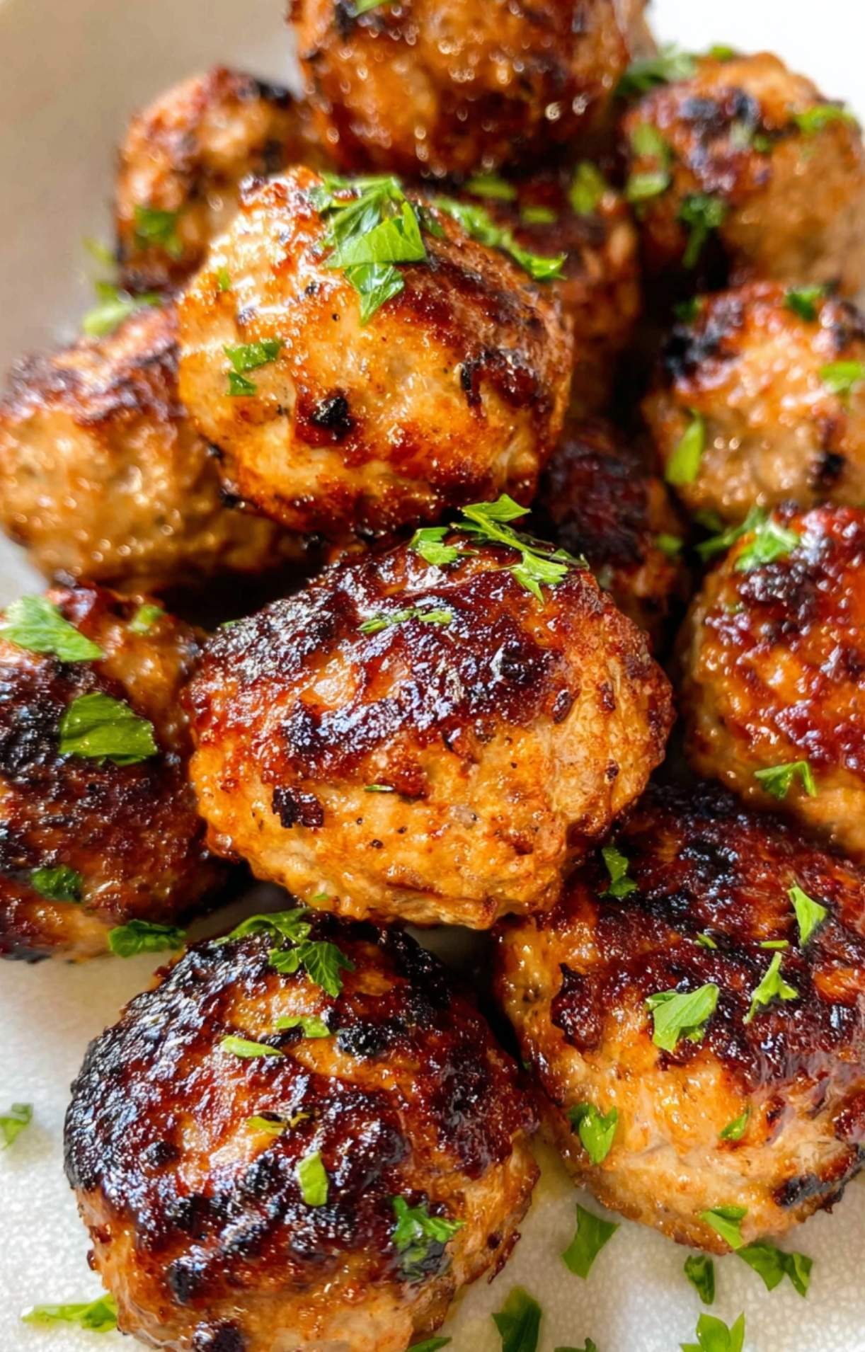 Extreme close-up of a crispy, browned healthy turkey meatball showing texture and herb garnish.