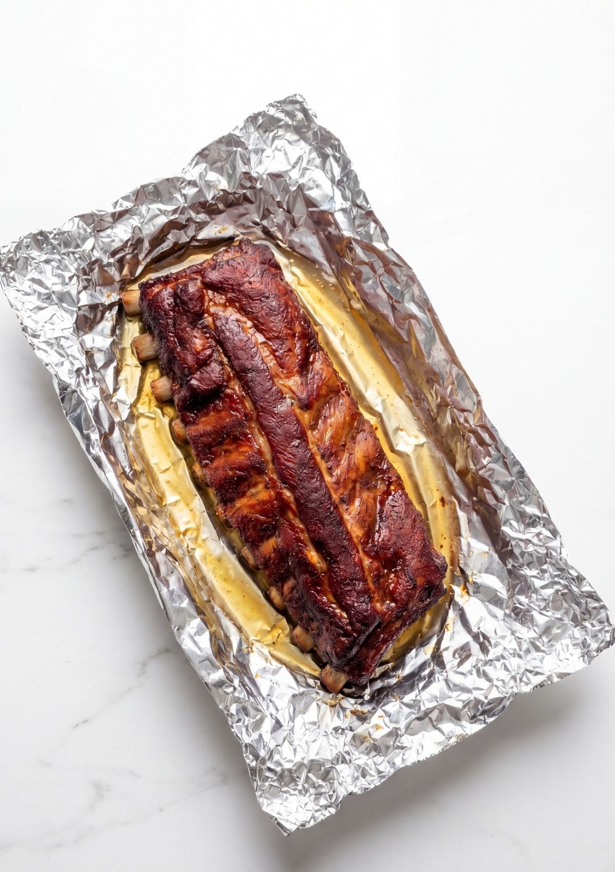 Pit Boss pellet smoker rib recipe showing ribs wrapped in foil with juices for moist tender BBQ ribs