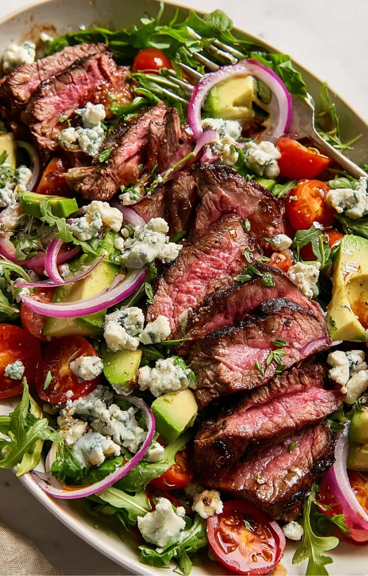 A delicious Steak and Blue Cheese Salad featuring juicy medium-rare beef slices, creamy avocado, and tangy blue cheese dressing.