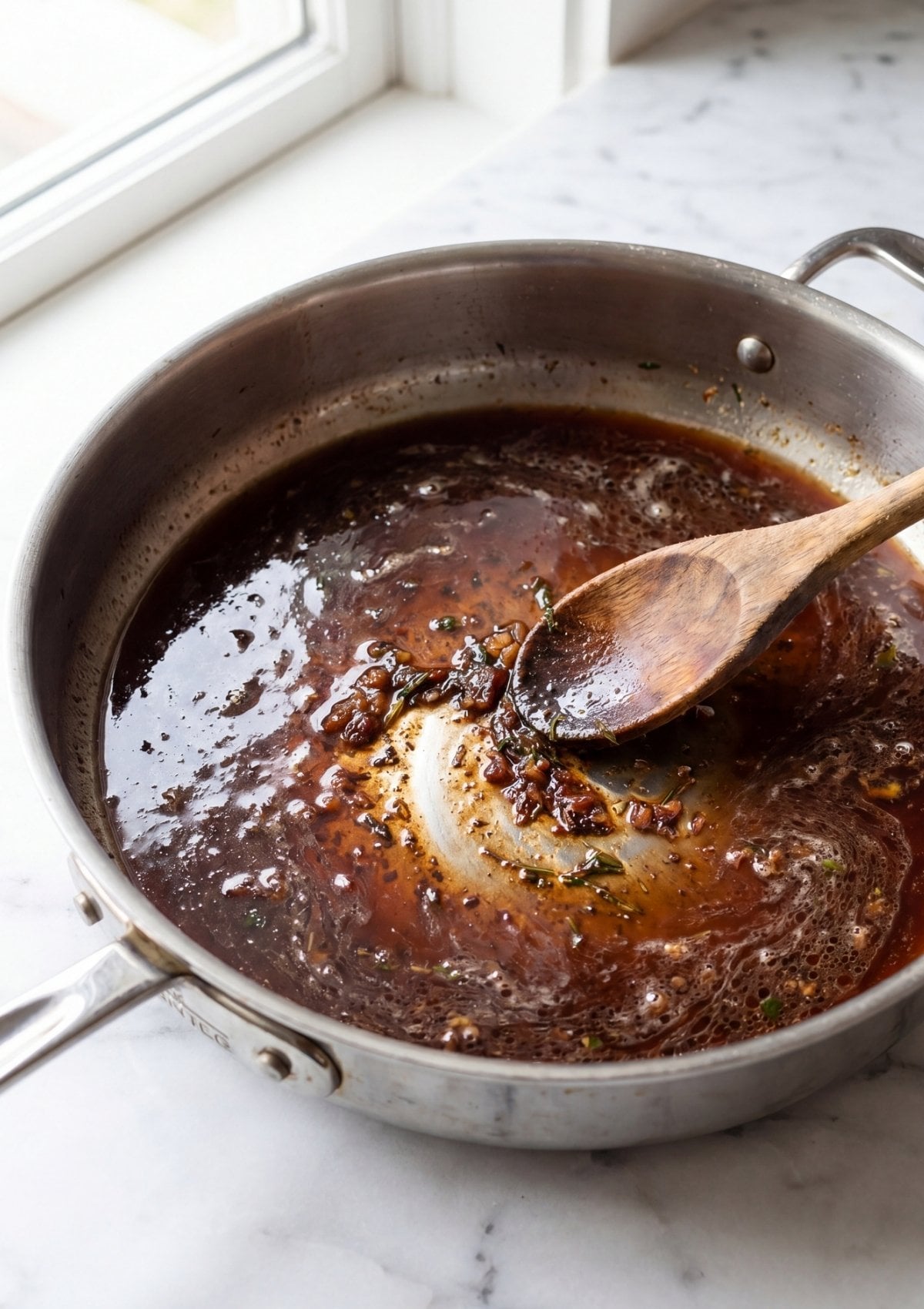 simmering sauce in pan for wagyu beef cheek recipe with herbs and broth