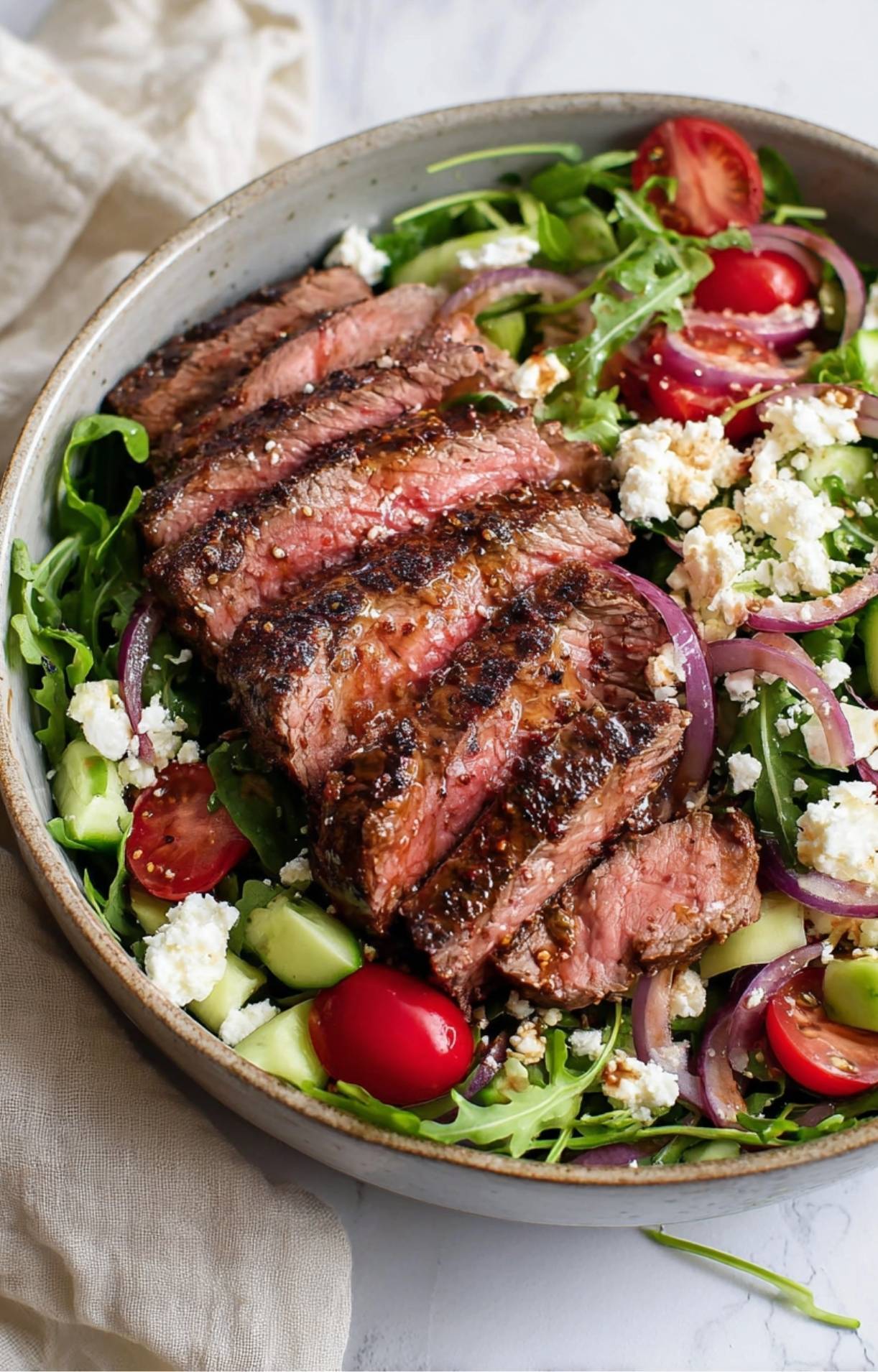 An angled view of a finished Healthy Steak Salad Recipe bowl, highlighting the vibrant colors of fresh vegetables and the juicy texture of the grilled beef.