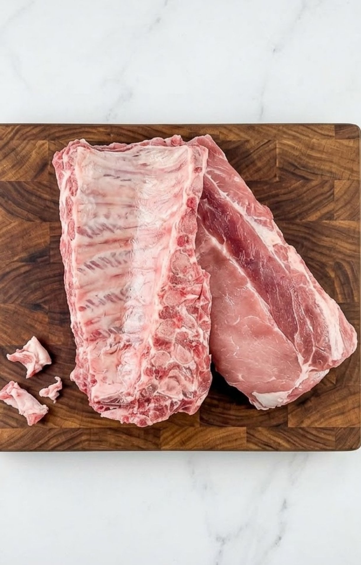 Raw baby back ribs prepped on a wooden cutting board with a clean white marble background for a pellet smoker recipe.