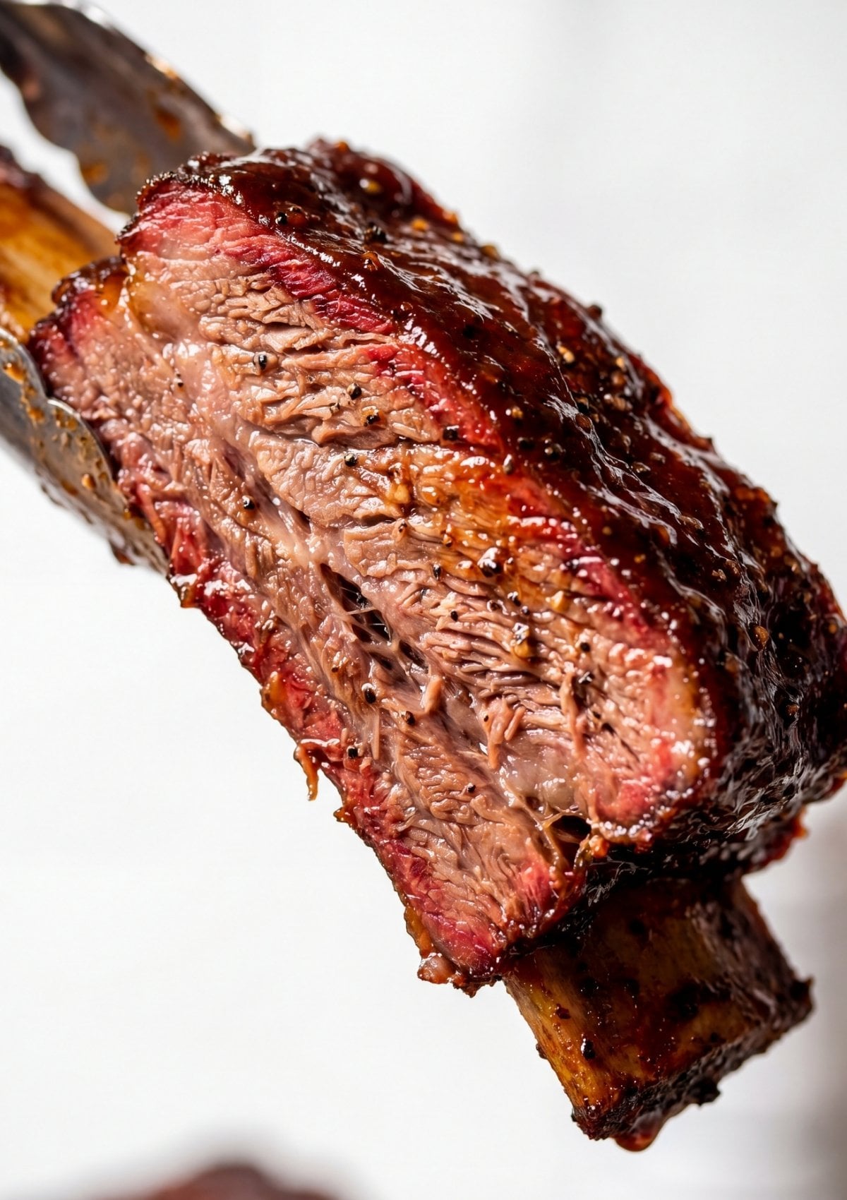 beef ribs pellet smoker recipe close up of smoked rib showing juicy interior and rich BBQ glaze