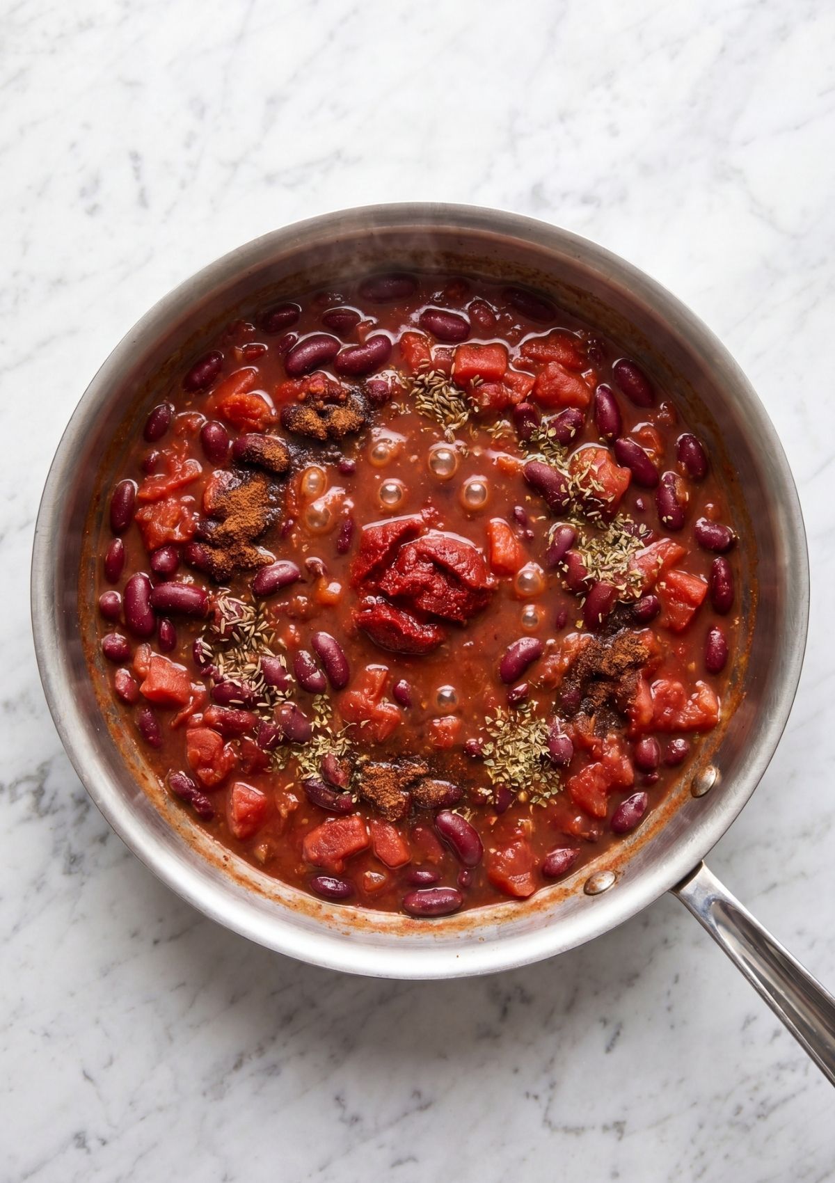 tomato sauce with beans and spices simmering for cowboy spaghetti with bacon easy dinner recipe