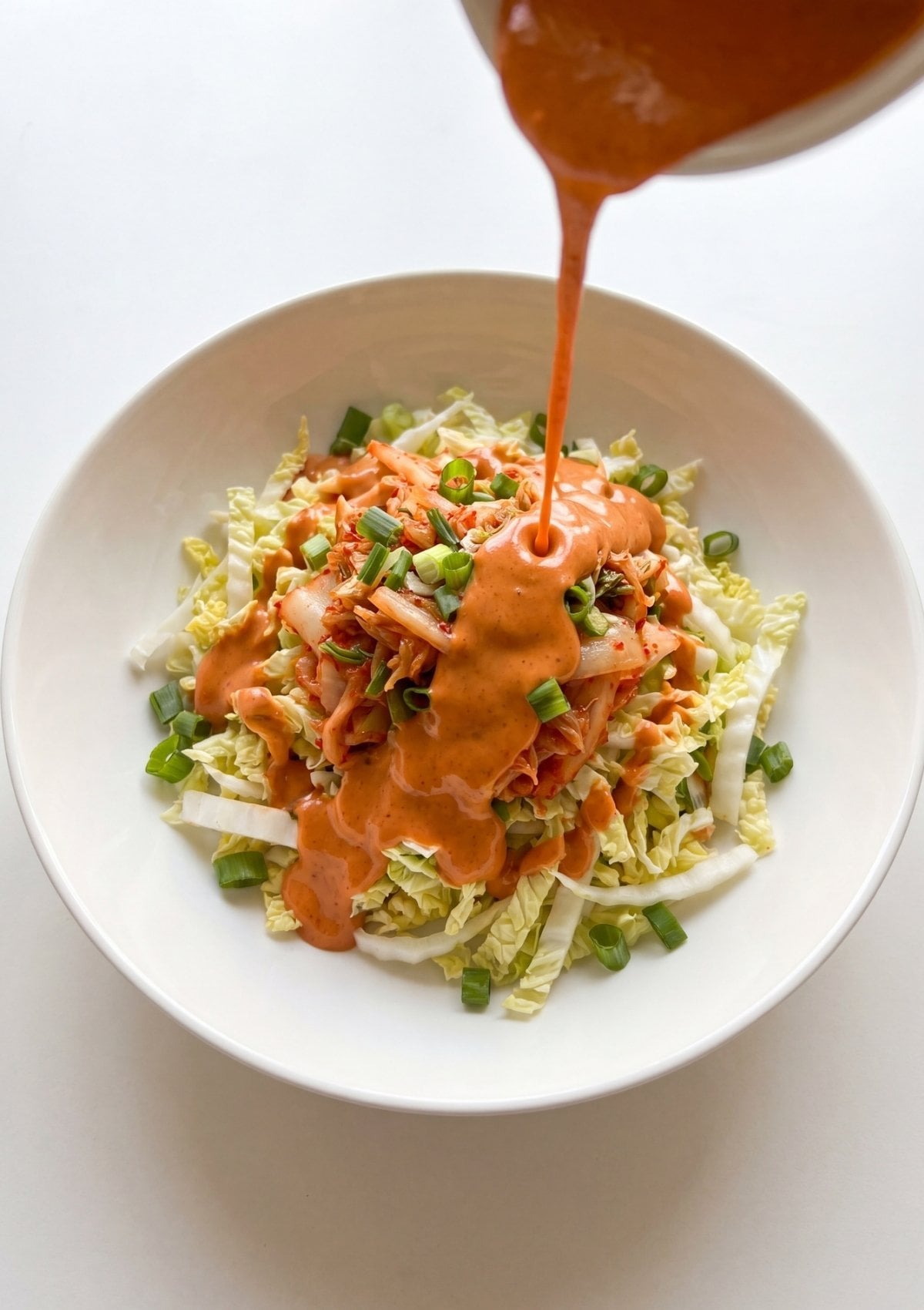 sauce poured over cabbage and kimchi slaw for wagyu beef hot dogs easy recipe step