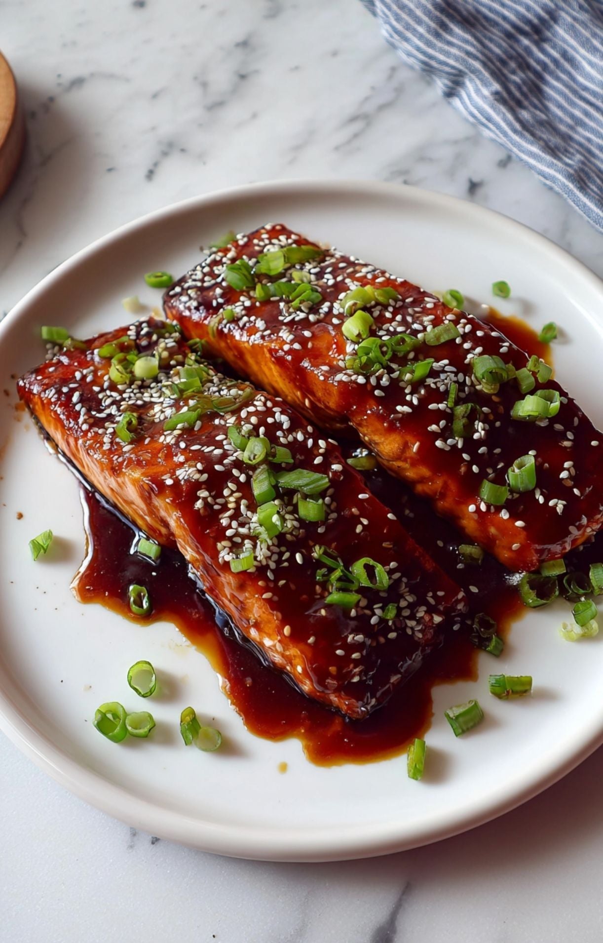 Side view of Teriyaki Air Fryer Salmon glistening with sauce and garnished with fresh scallions.