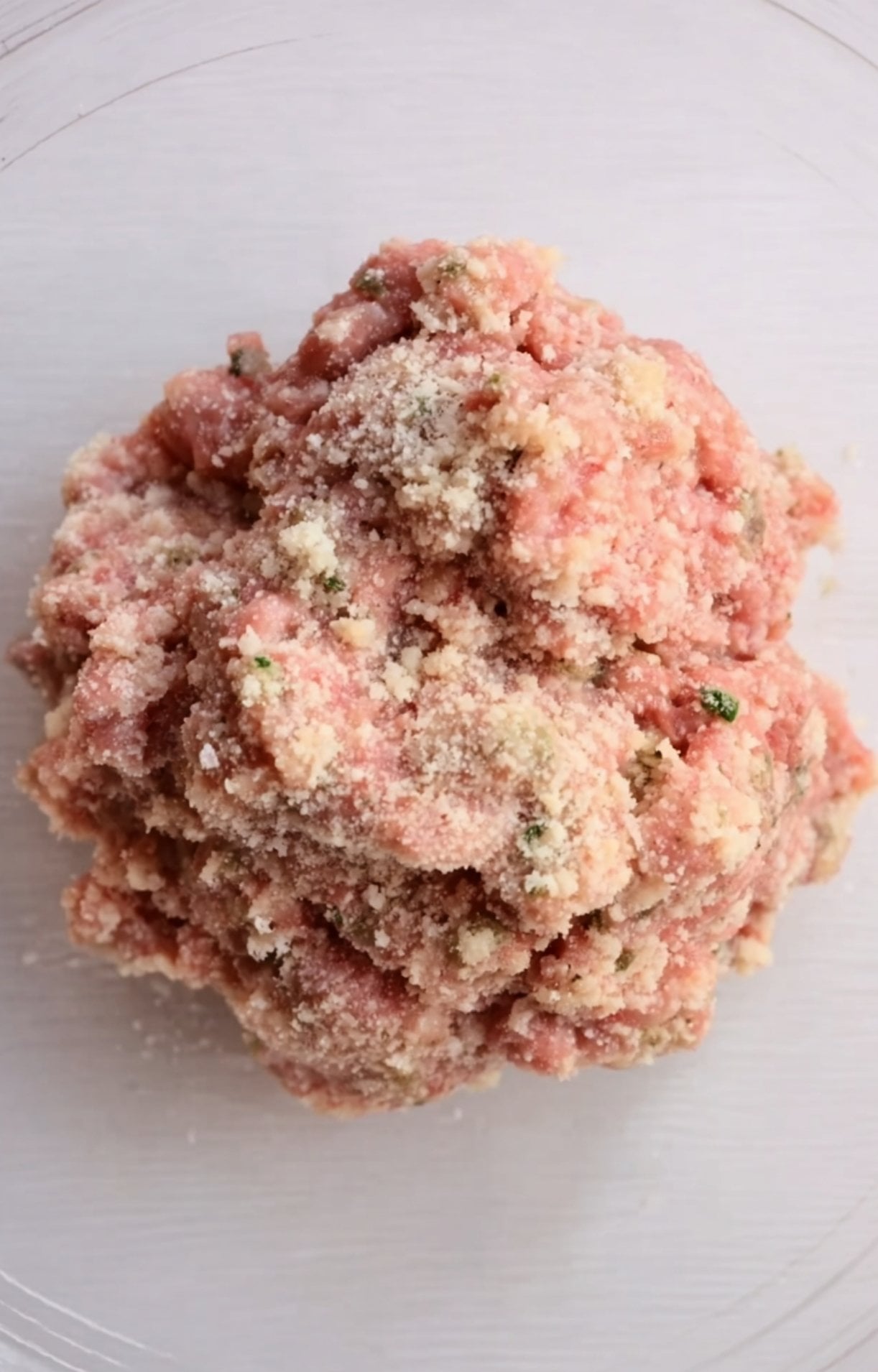 A close-up view of the raw meatball mixture after being thoroughly combined with breadcrumbs, herbs, and seasonings, ready to be rolled.