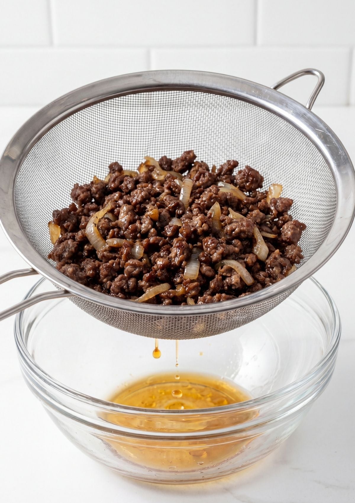 cooked wagyu beef draining in strainer removing excess grease for sliders