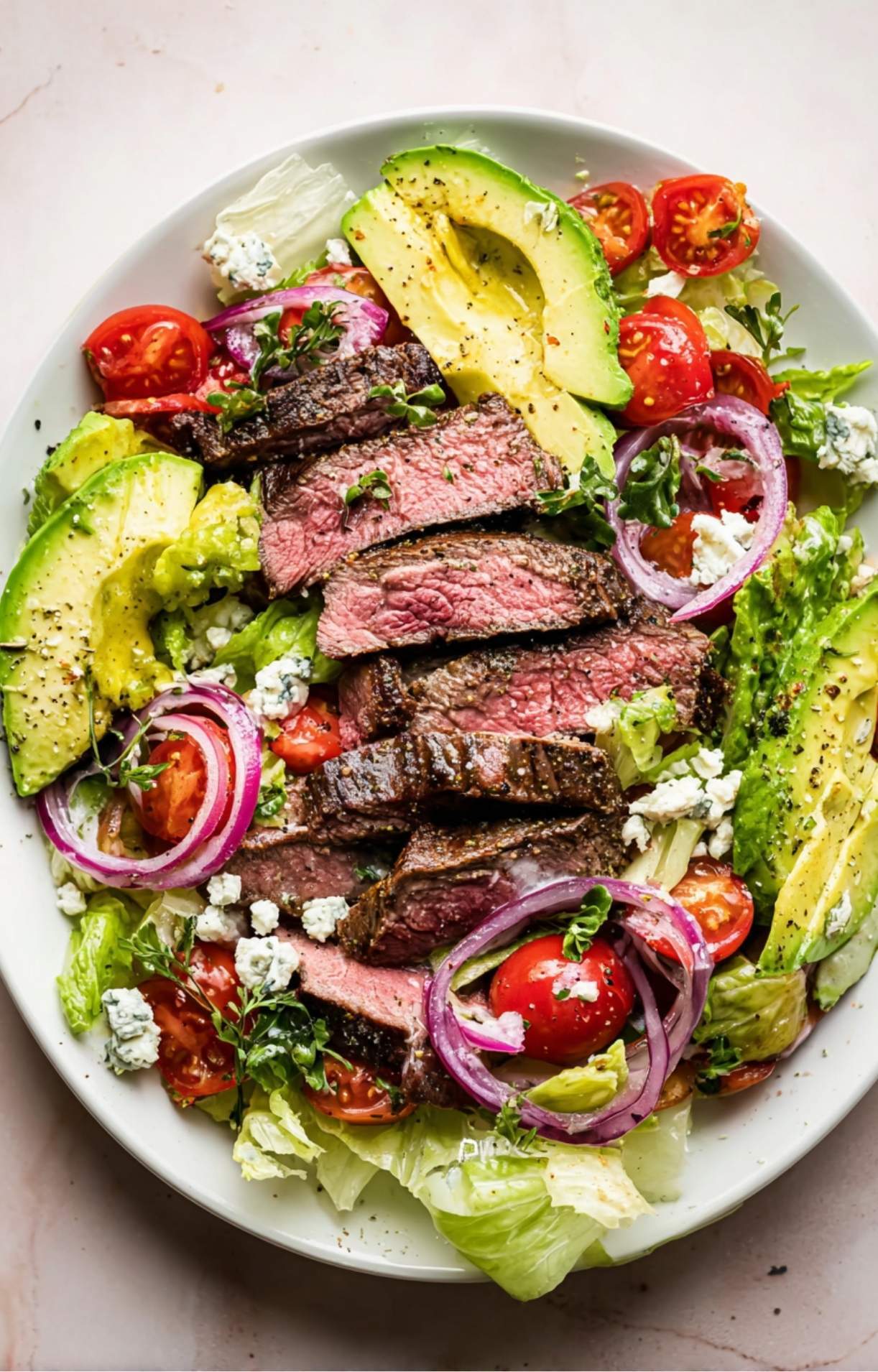 A colorful, high-protein salad bowl with seared steak strips, fresh vegetables, and a generous sprinkle of blue cheese.
