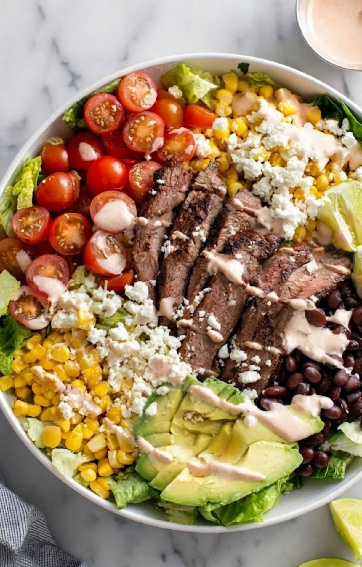 A top-down view of an Easy Steak Taco Salad Recipe bowl featuring organized sections of toppings and a drizzle of spicy crema.