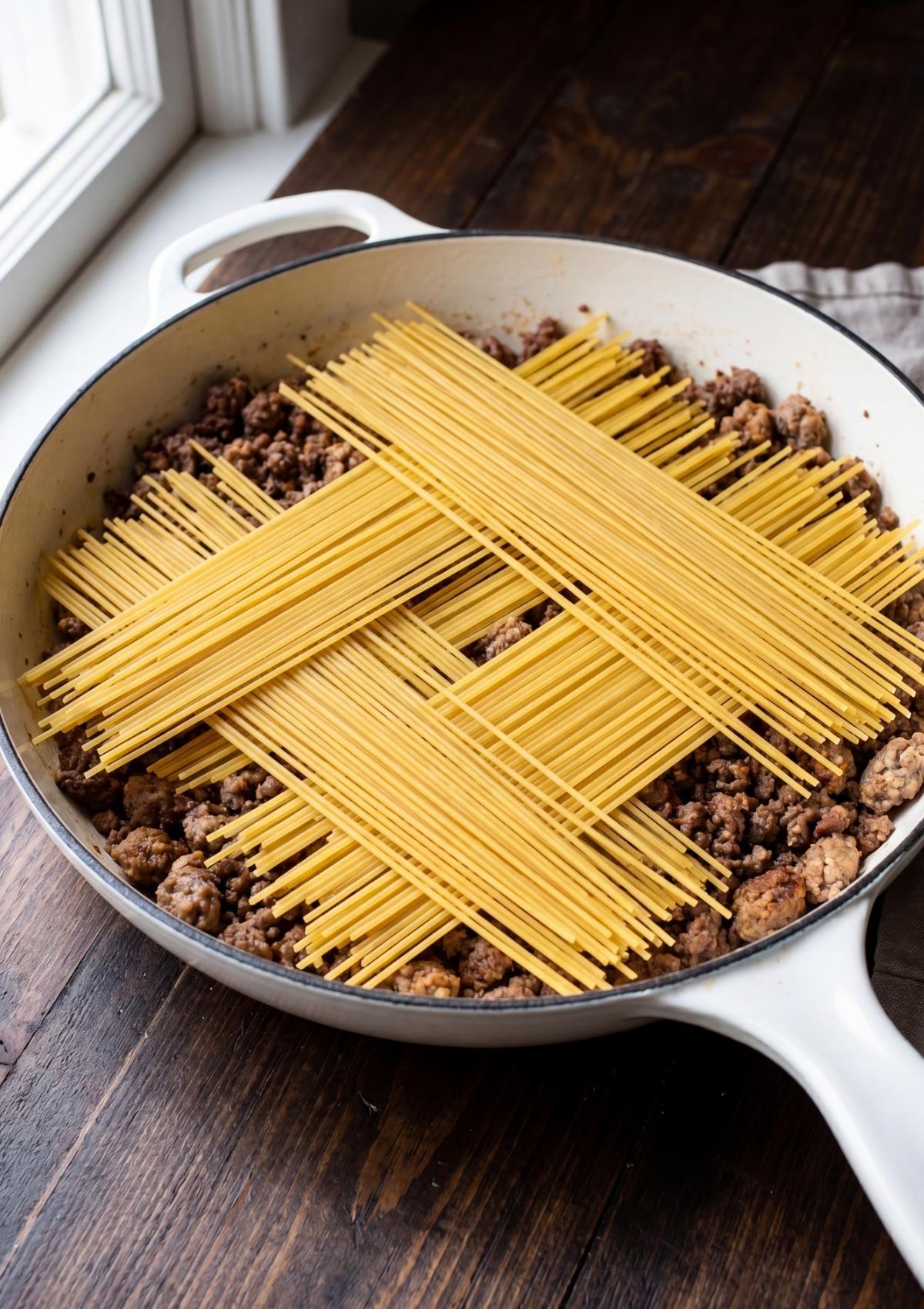 dry spaghetti added to skillet for one pot cowboy spaghetti easy cooking method