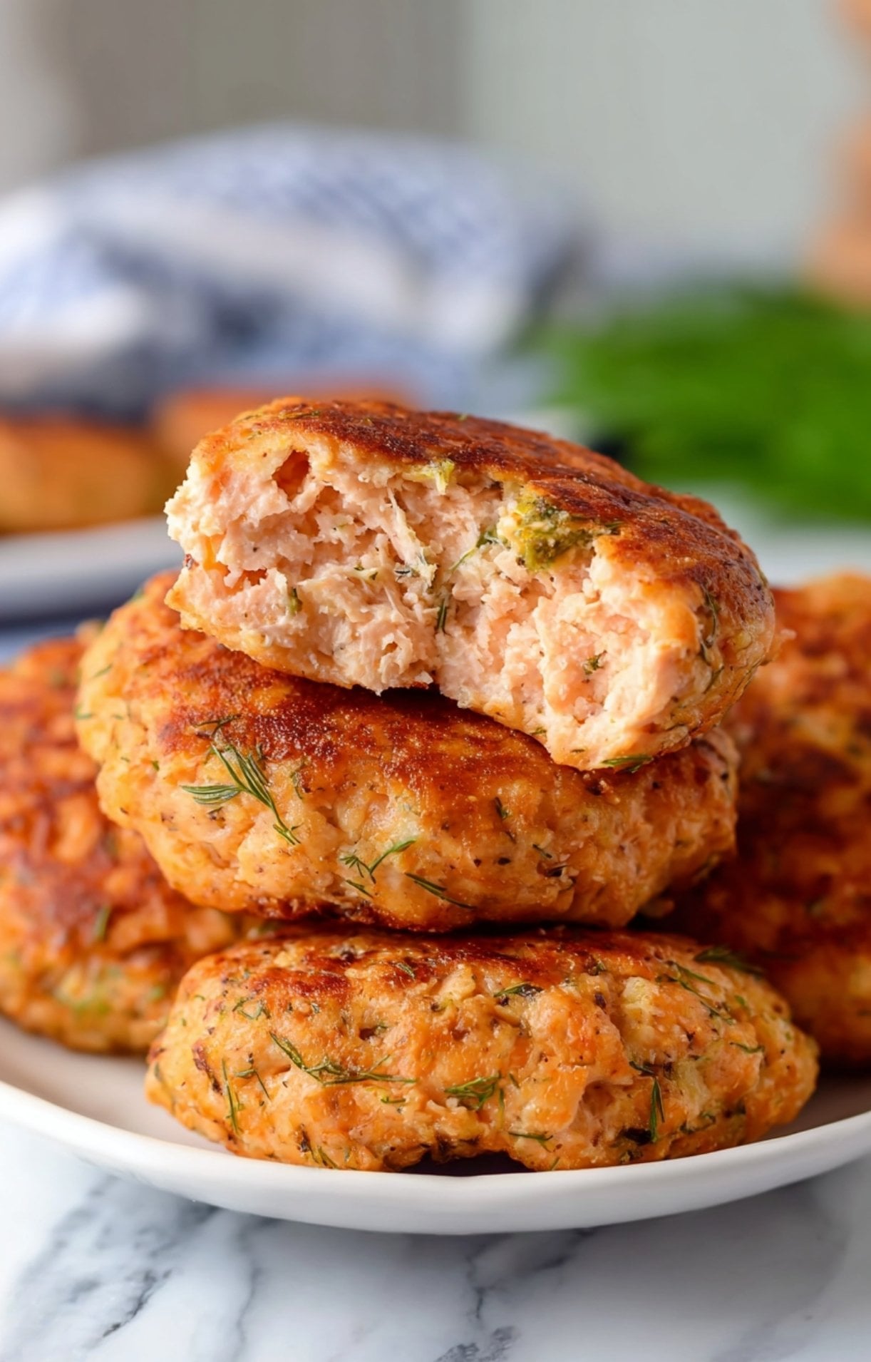 A stack of perfectly cooked air fryer salmon patties showing a close-up of the tender, seasoned fish inside.
