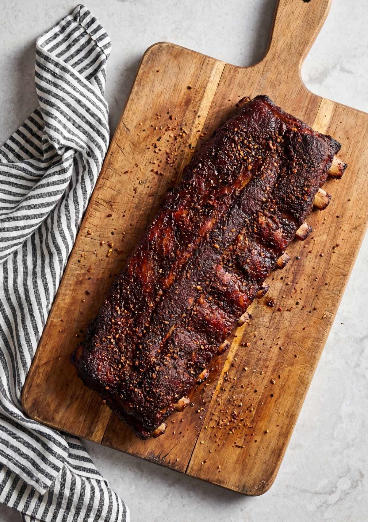 full rack of pellet smoker memphis ribs recipe on wooden board with dark bark and dry rub seasoning