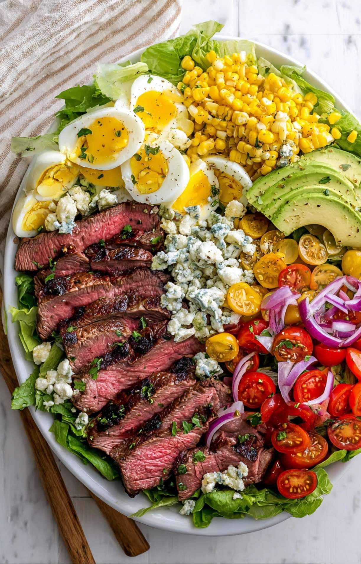 A detailed close-up shot of a Steak Cobb Salad highlighting the charred steak edges, creamy blue cheese, and vibrant vegetables.