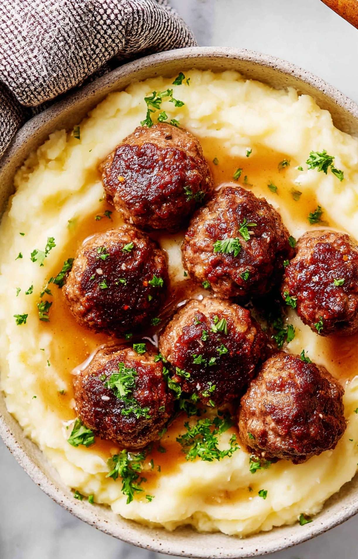 An overhead view of air fryer beef meatballs nestled in mashed potatoes with a savory pan gravy.