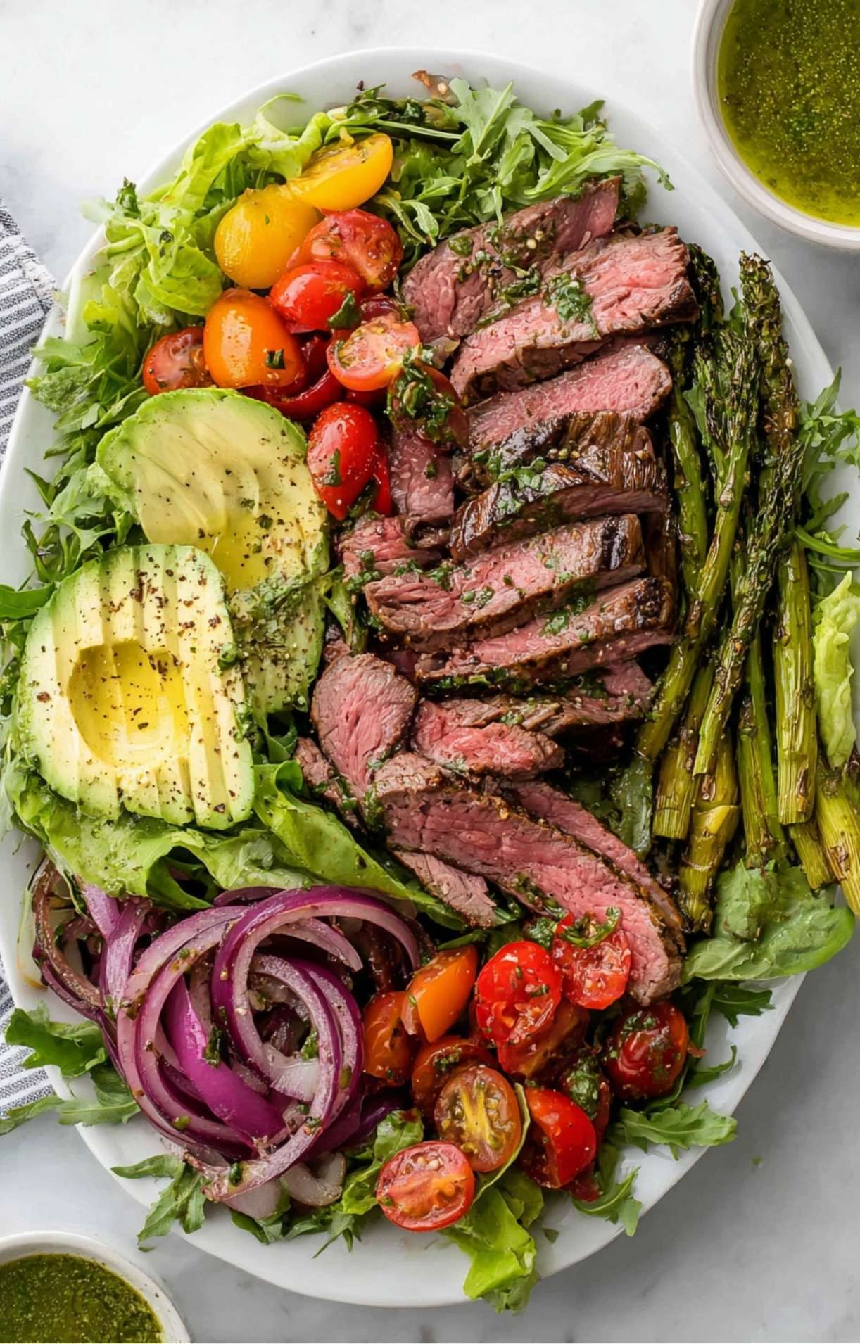 A top-down view of the colorful Chimichurri Steak Salad featuring vibrant vegetables and tender beef arranged beautifully on a large white plate.