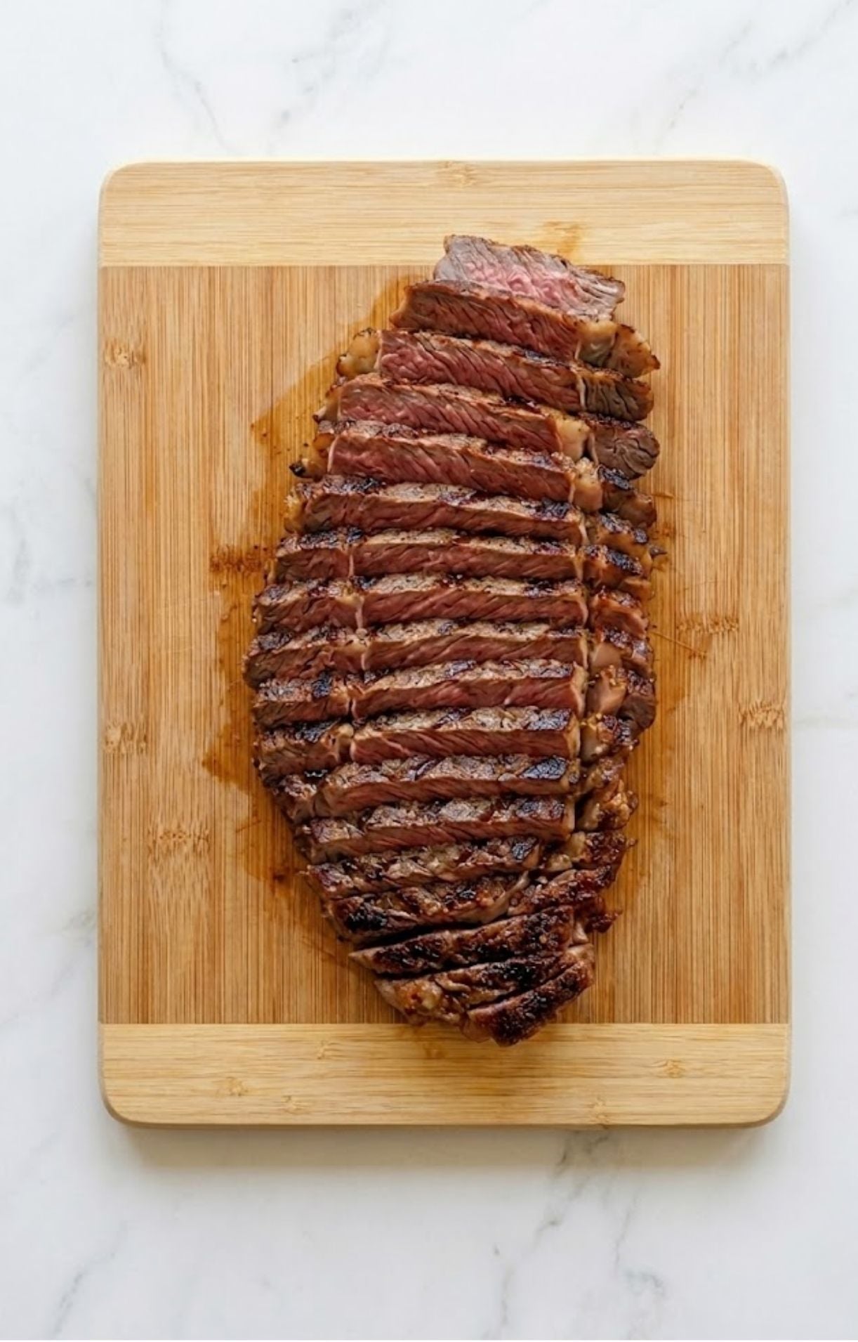 Perfectly rested and sliced grilled steak on a wooden cutting board, ready to be added to a Healthy Steak Salad Recipe.