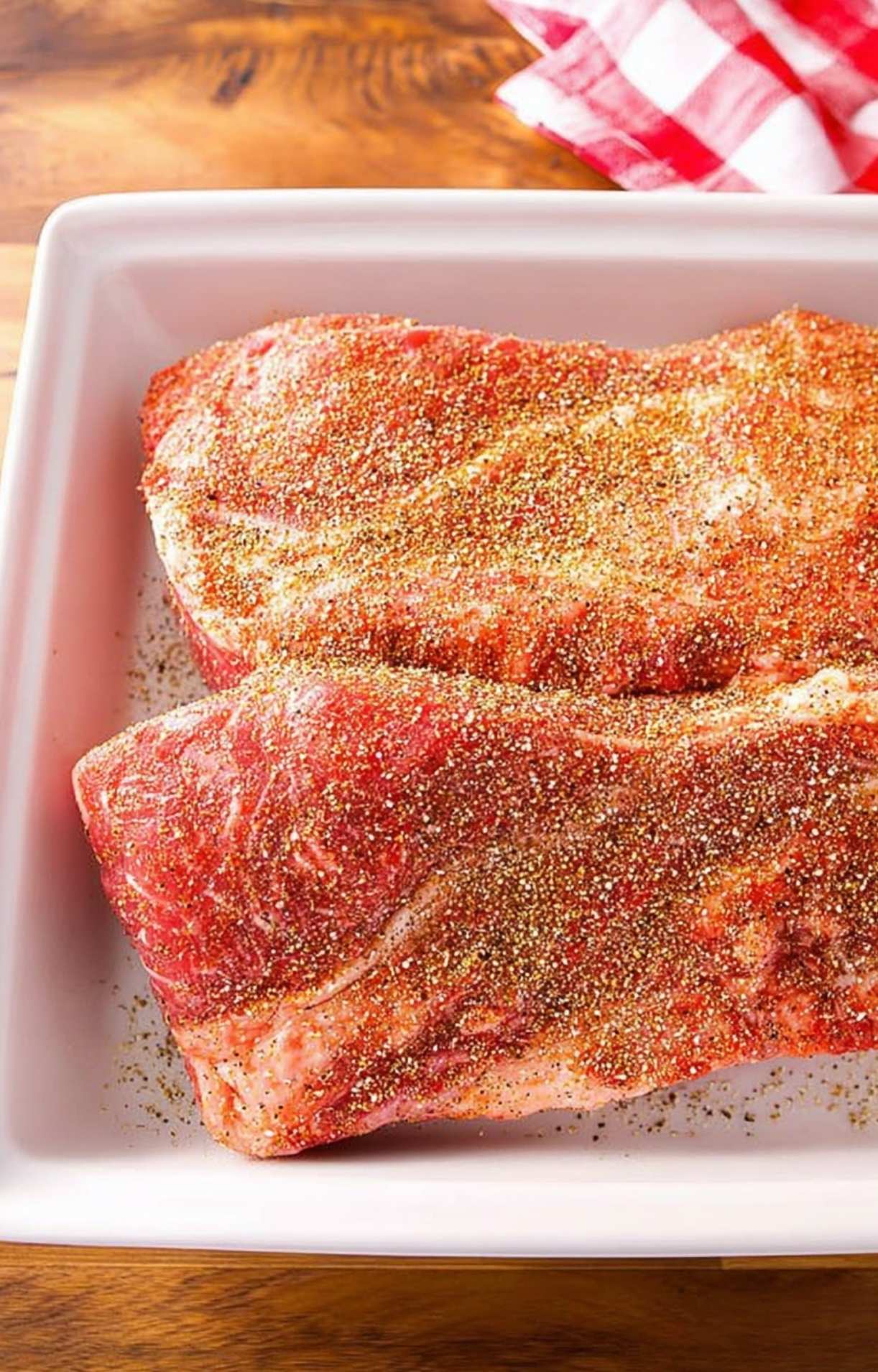 Beef short ribs pellet smoker recipe with seasoning rubbed on raw beef ribs in tray ready for smoking