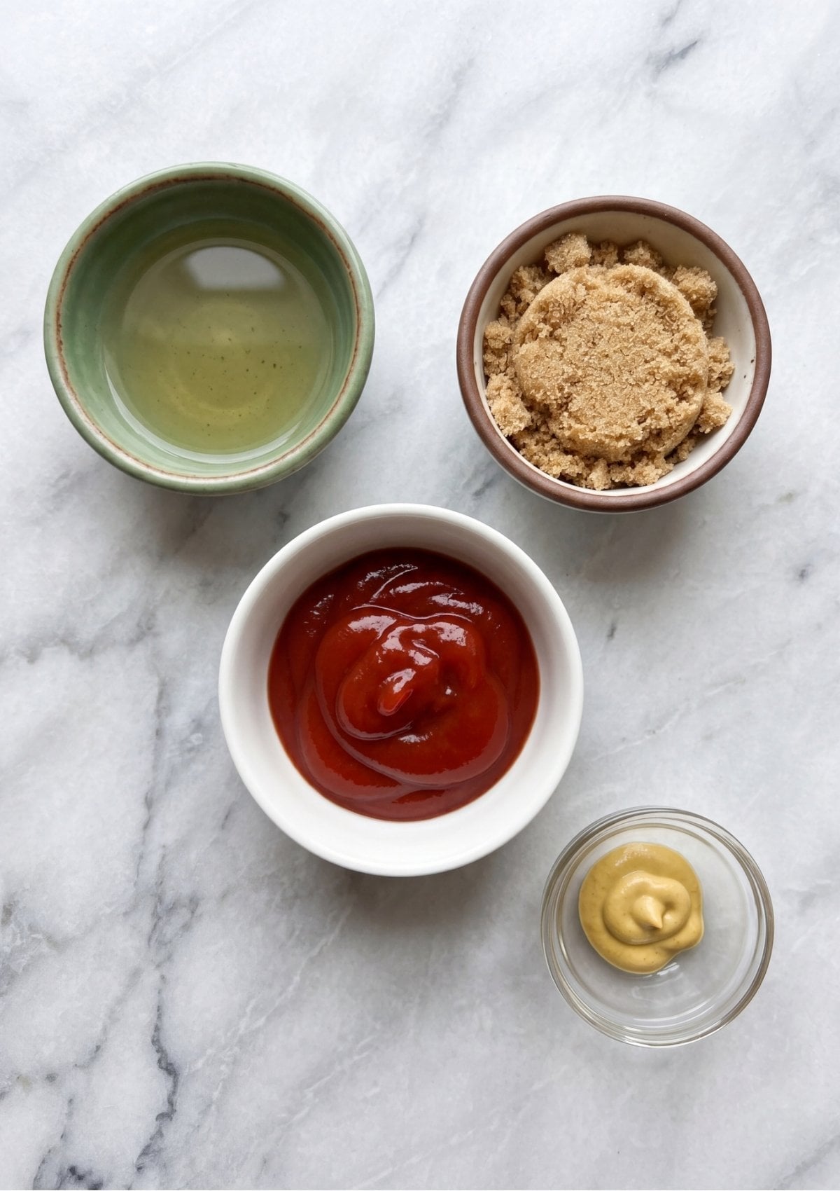 Four small bowls containing ketchup, brown sugar, mustard, and vinegar for a Meatloaf Glaze Recipe.