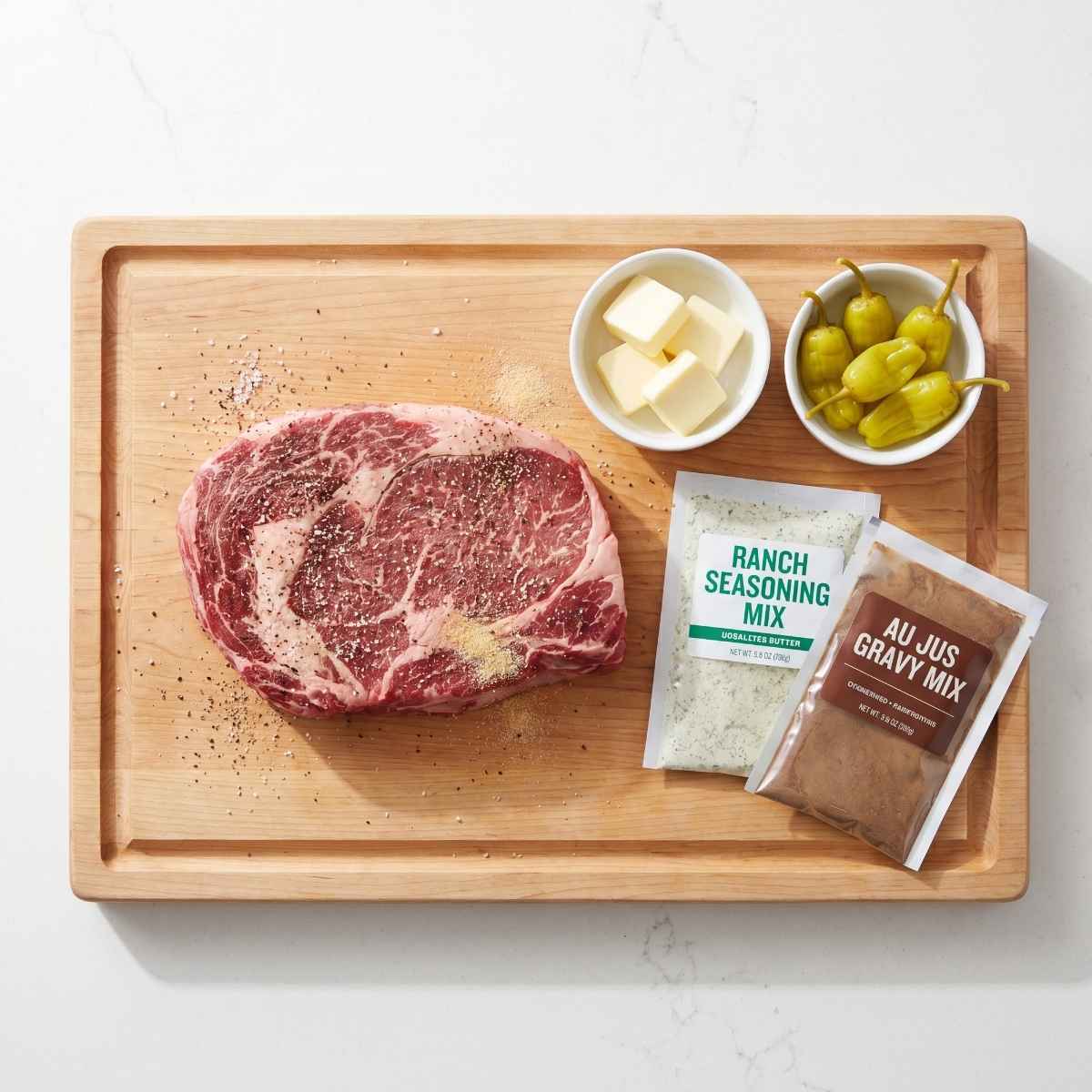 ingredients-for-smoked-mississippi-pot-roast-including-raw-chuck-roast-butter-pepperoncini-and-seasoning-packets