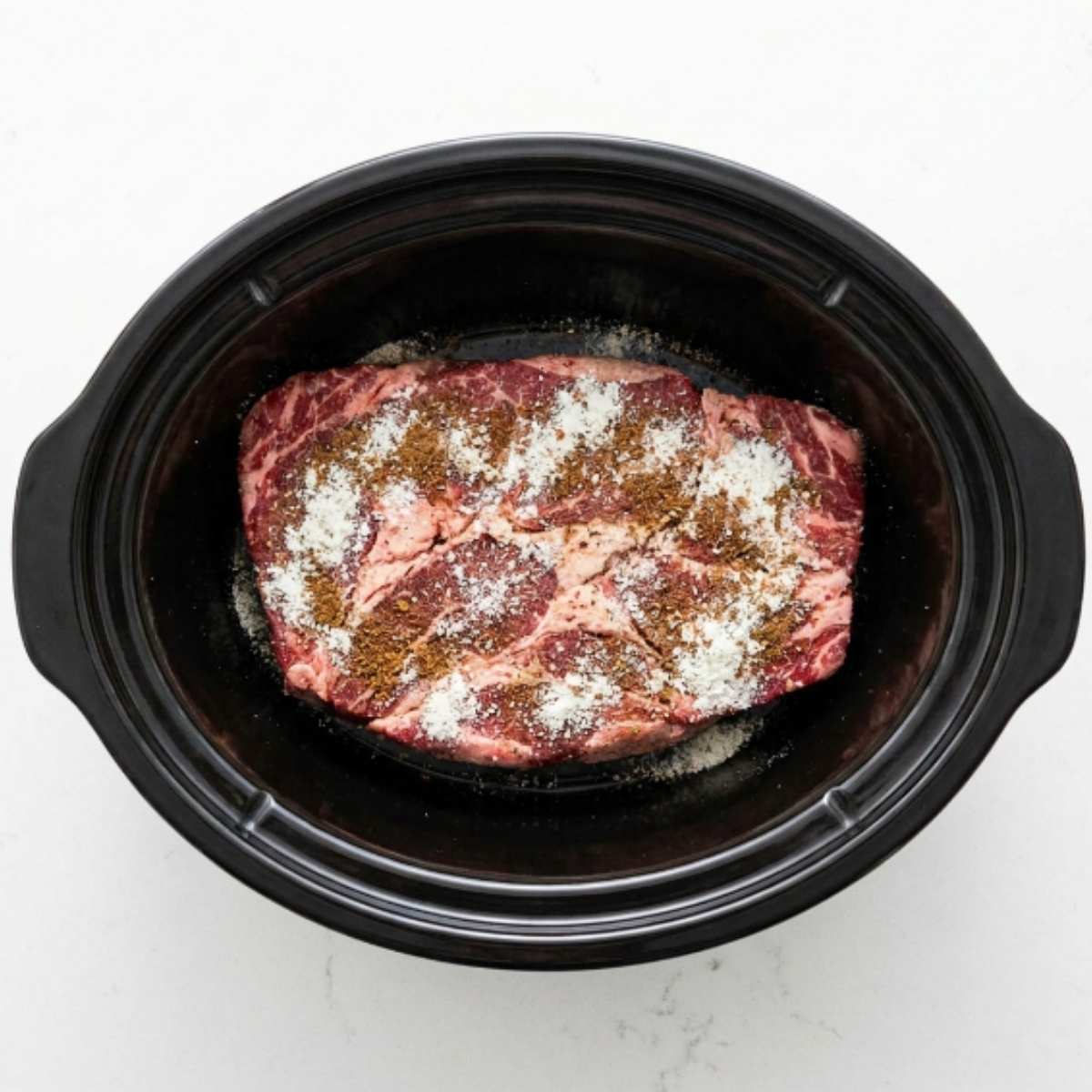 raw-chuck-roast-in-a-slow-cooker-sprinkled-with-ranch-and-au-jus-seasoning-packets