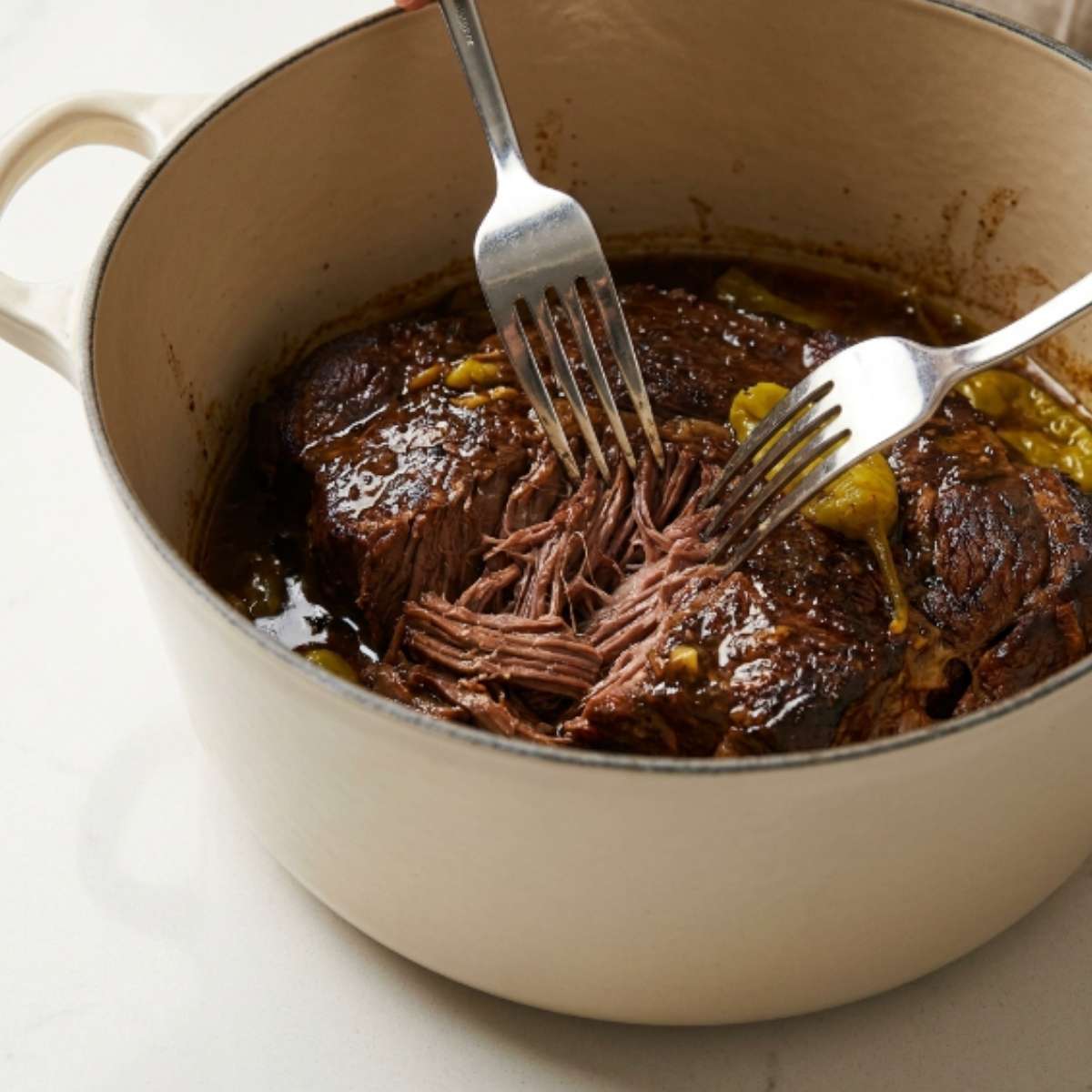 shredding-cooked-mississippi-pot-roast-with-two-forks-inside-a-white-dutch-oven