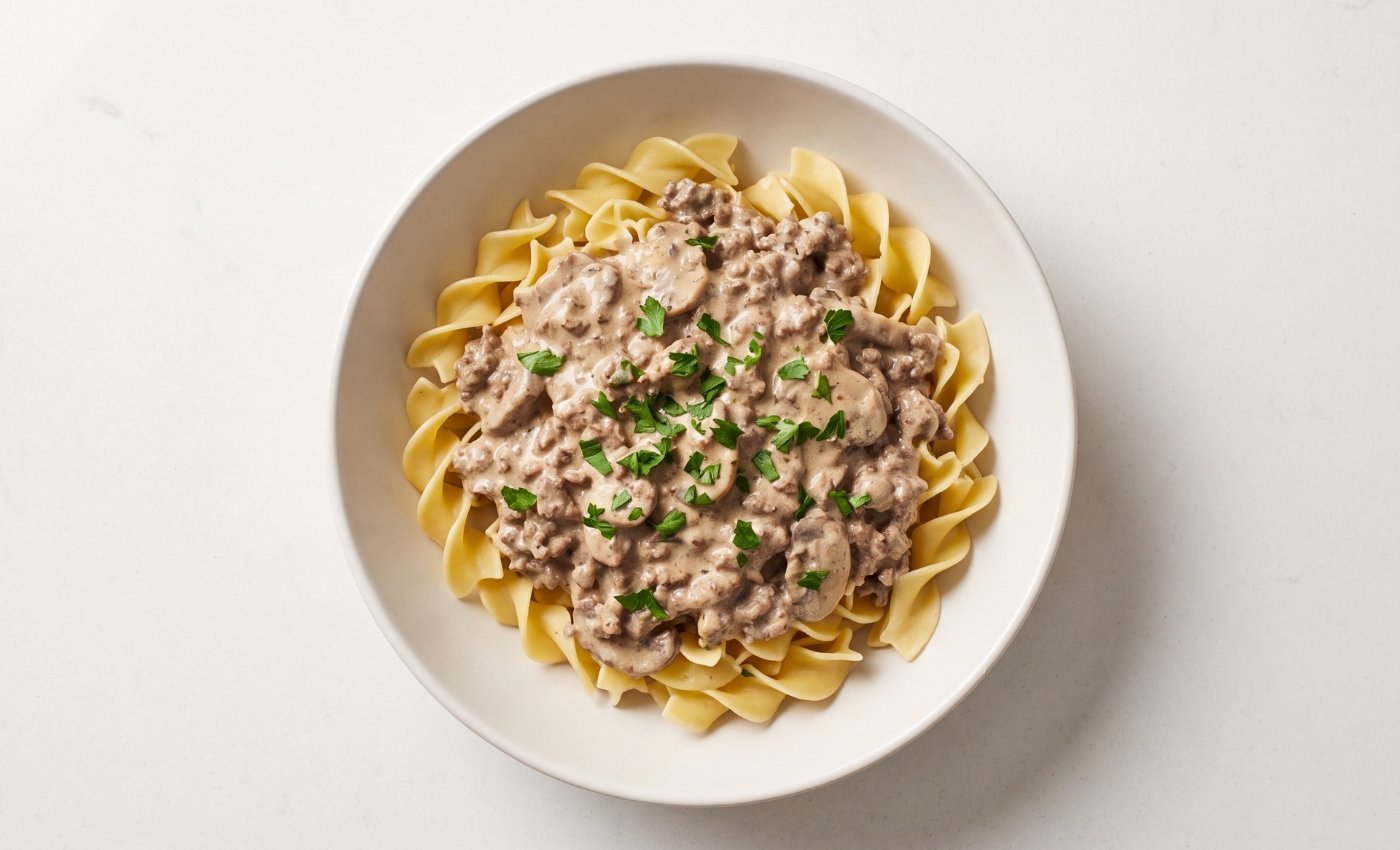 A bowl of homemade ground beef stroganoff with a smooth sauce and fresh parsley garnish over egg noodles